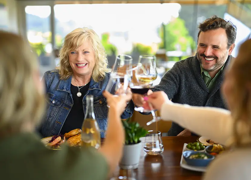 A group of people gathered around a table raising a toast with wine.