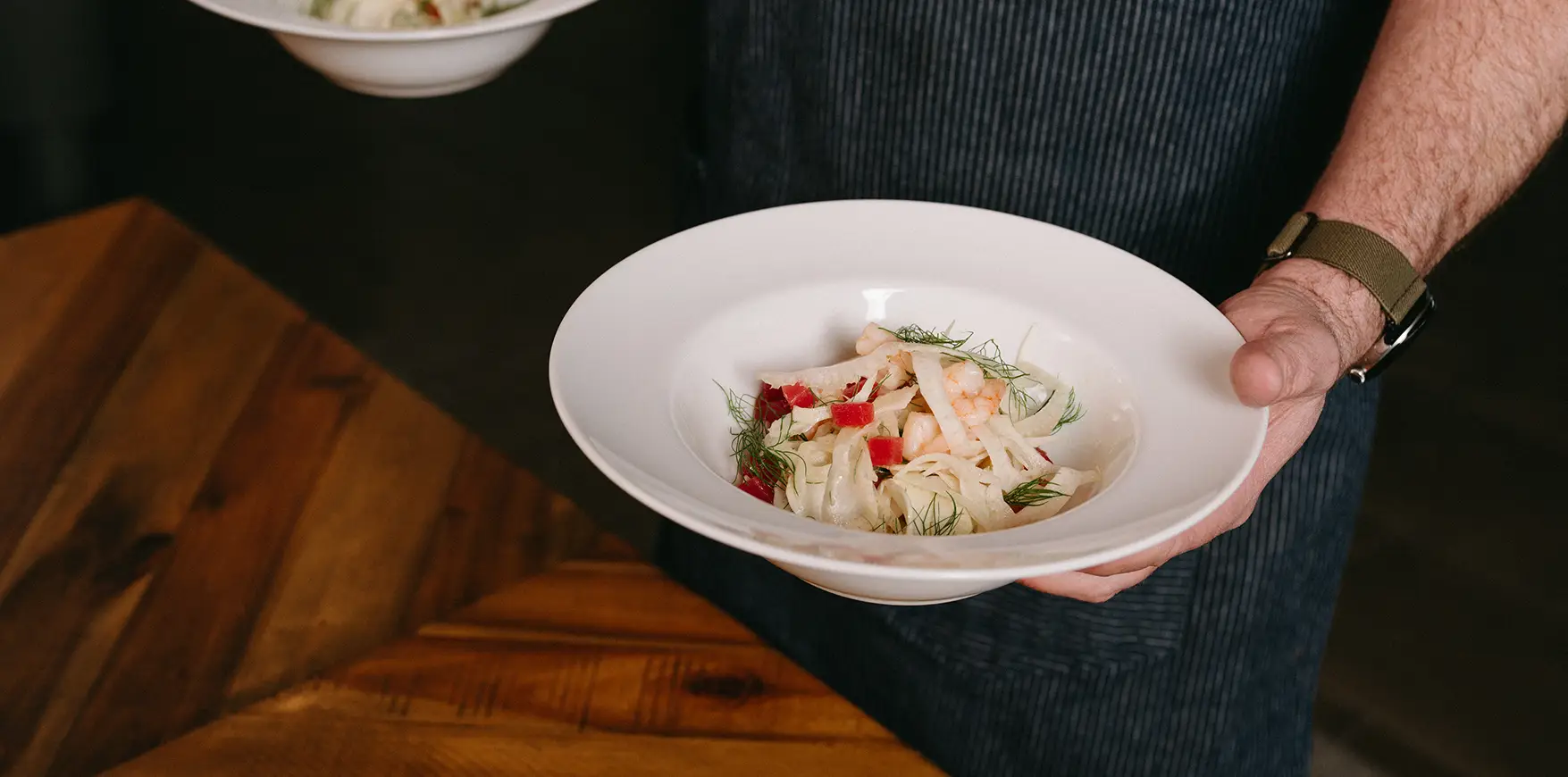 Chef holding two plated meals.