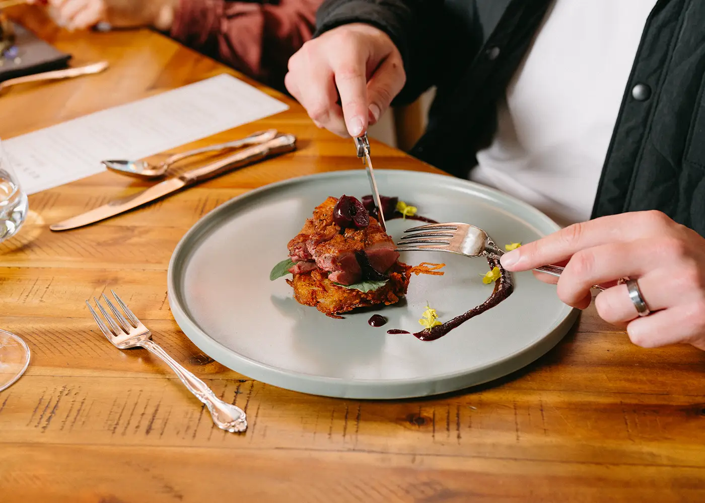 Person holding a knife and fork about to cut in to a plate of delicious food.