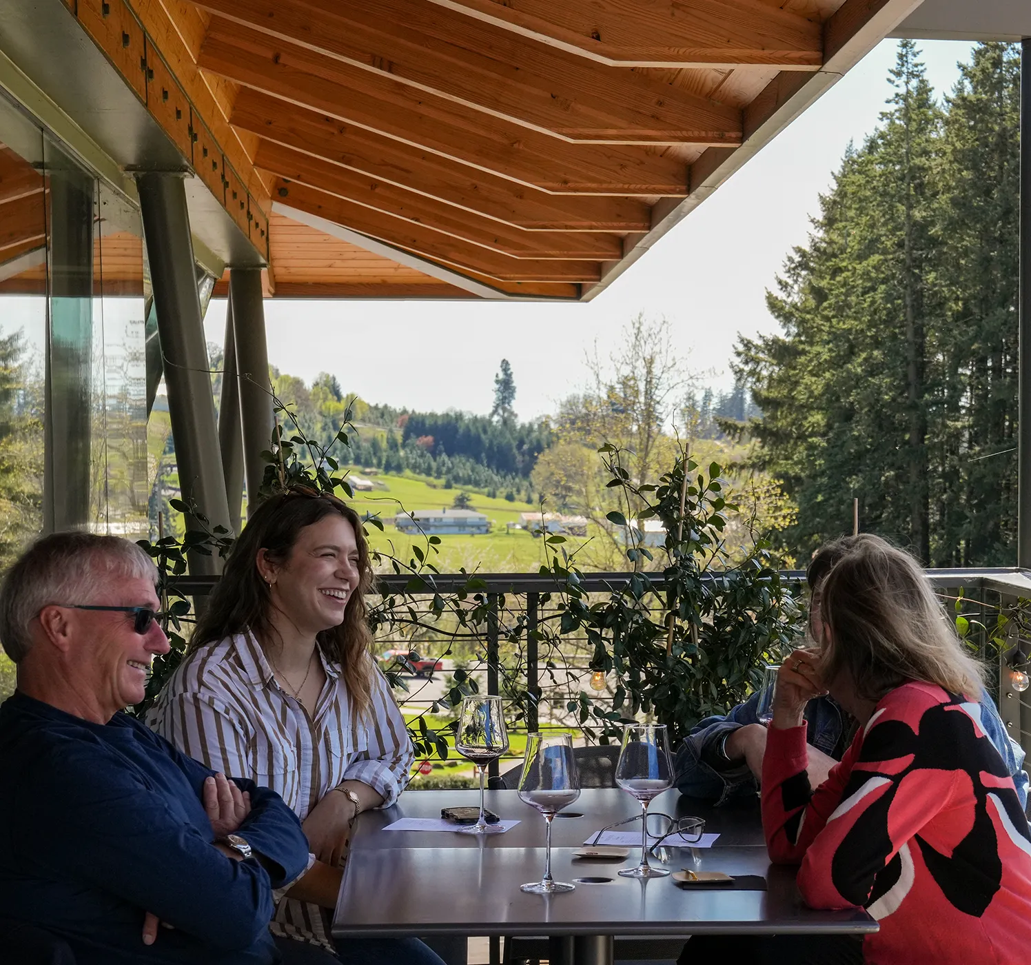 Friends enjoying Rex Hill wines sitting out on a deck surrounded by nature.