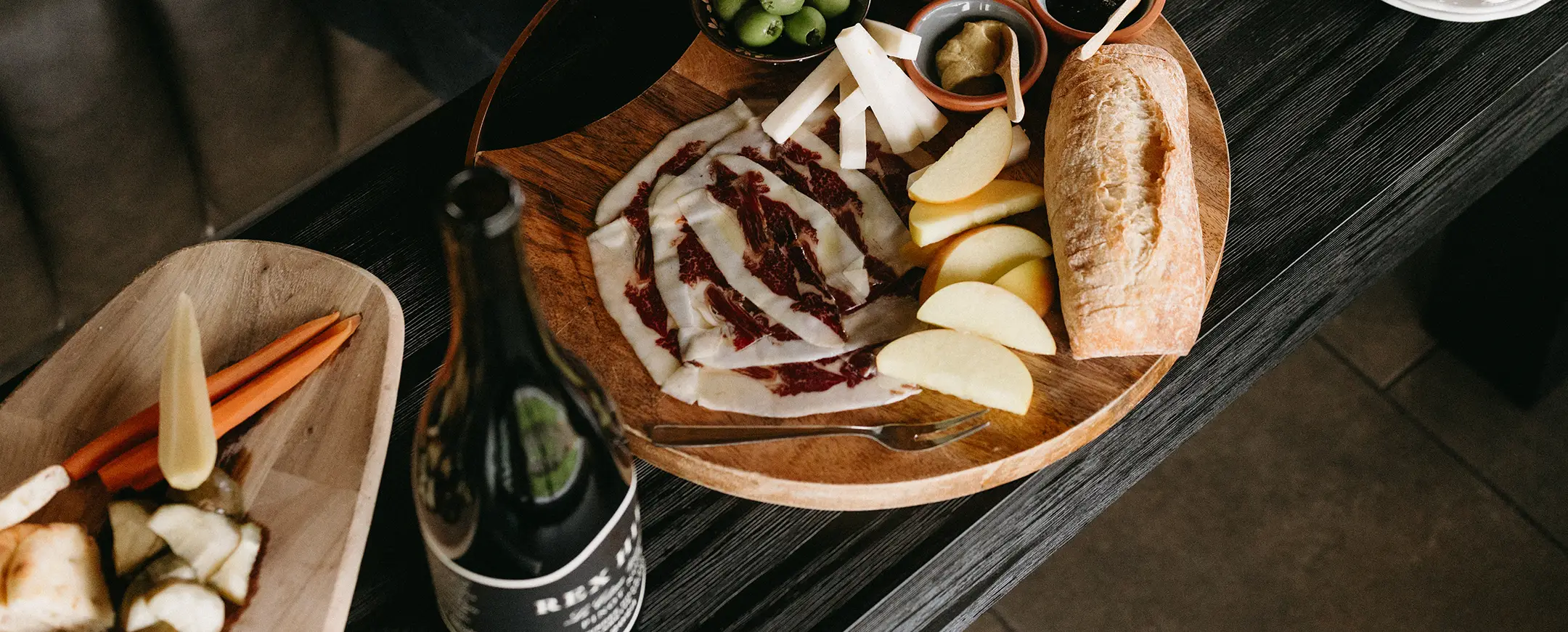 Charcuterie board on a coffee table with Rex Hill wines making the perfect pairing.